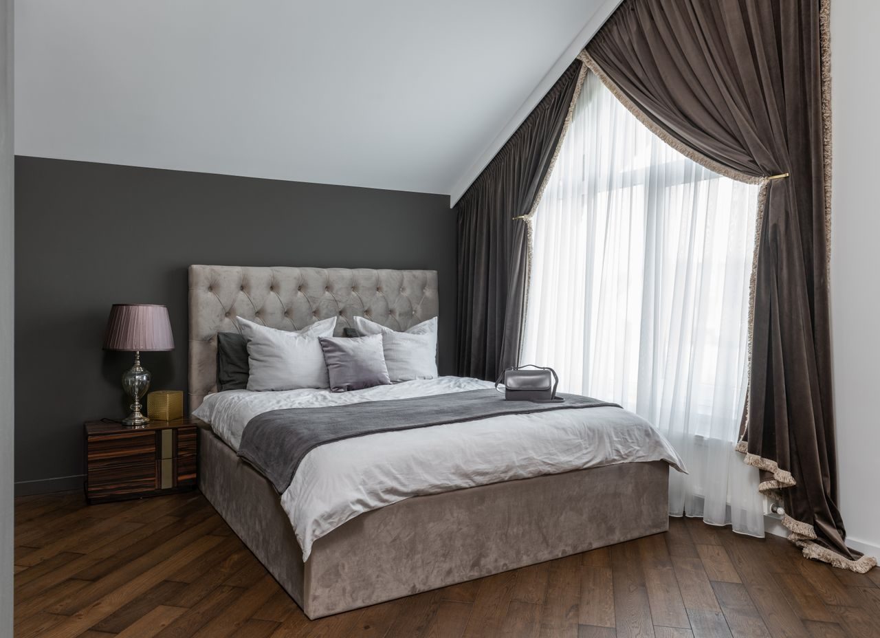 An adult bedroom with cushions, a blanket and bedside lighting
