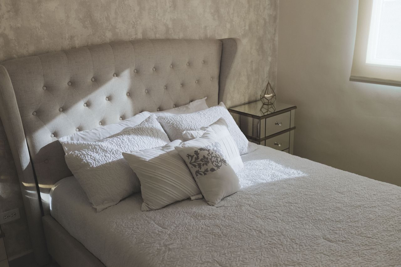 Soft bedding and pillows in a softly lit adult bedroom