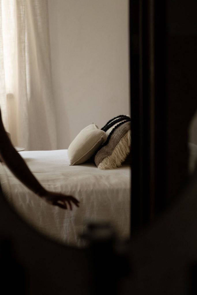 Light bed linen and pillows arranged in an adult bedroom