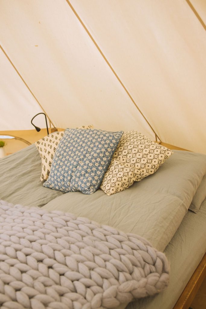 A soft blanket and patterned pillows on an adult bed